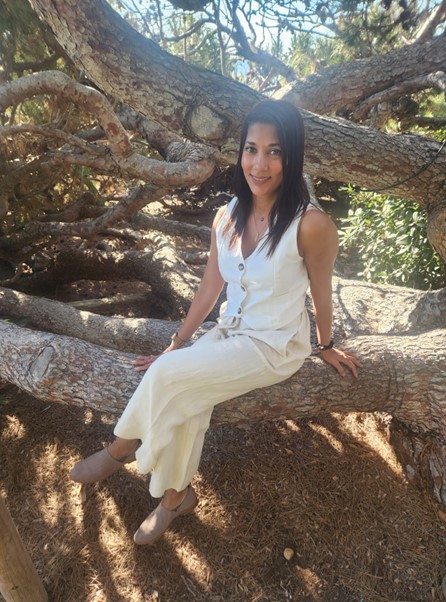 young woman sitting on tree branch wearing all white outdoors sunny day